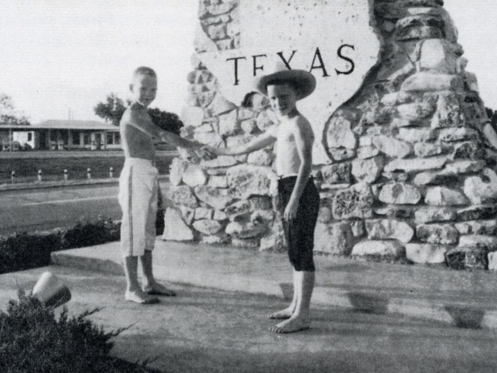 Two boys shake hands in front of a 