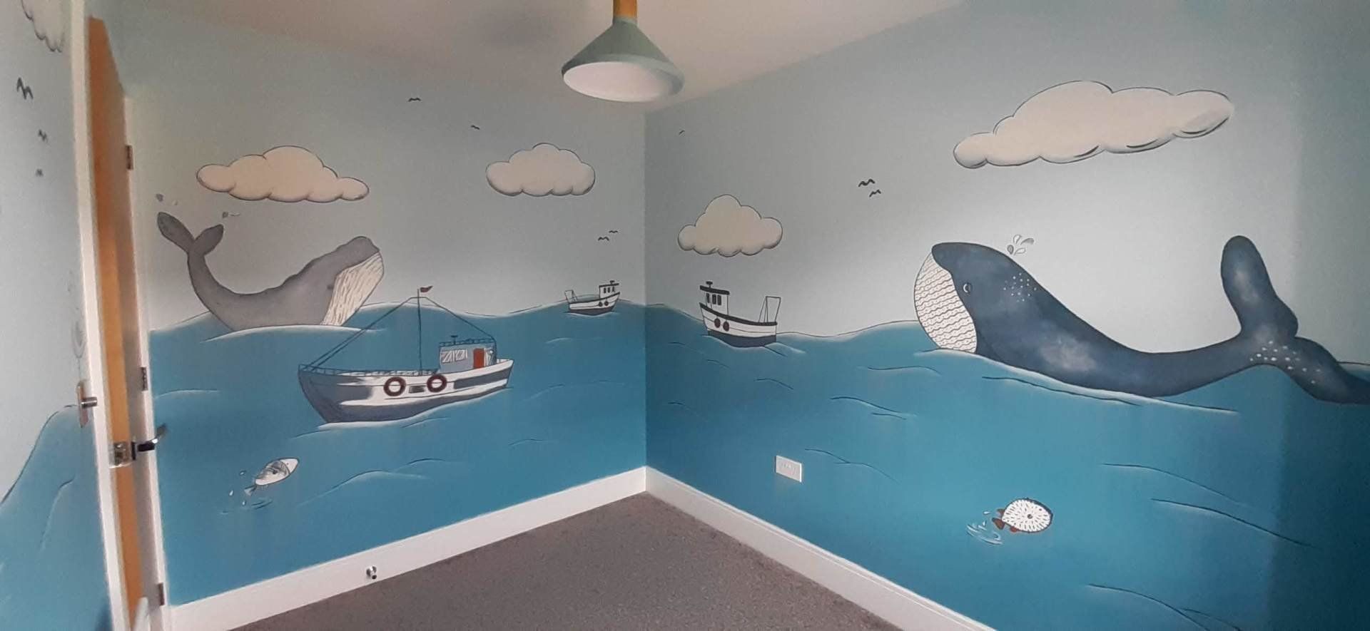 nursery mural with whales and boats in a sea scape