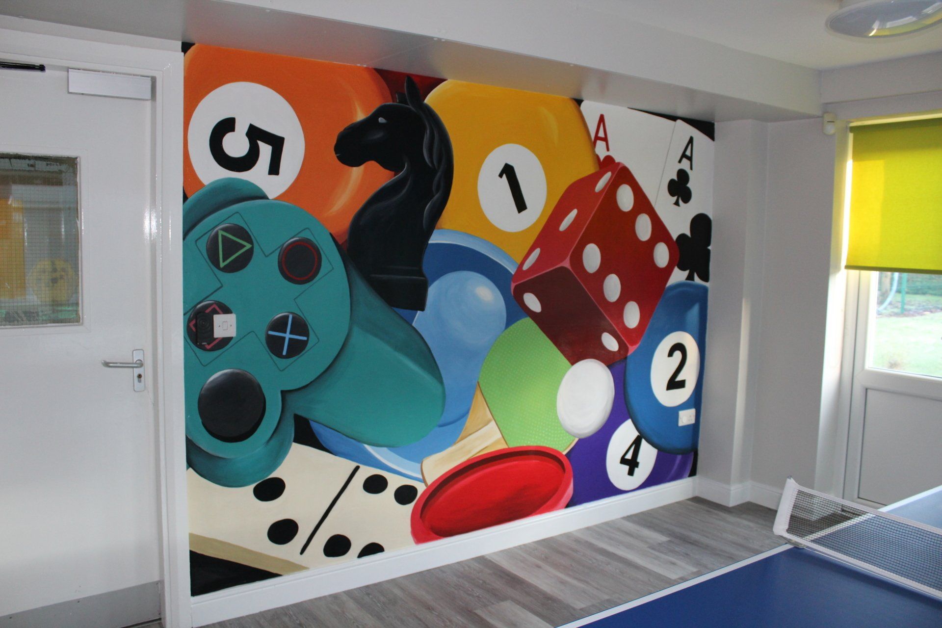 Games room mural in a children respite centre chess dice pool balls dominoes playing cards air hockey puck disk controller

