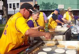 A group of people are cooking pancakes on a grill.