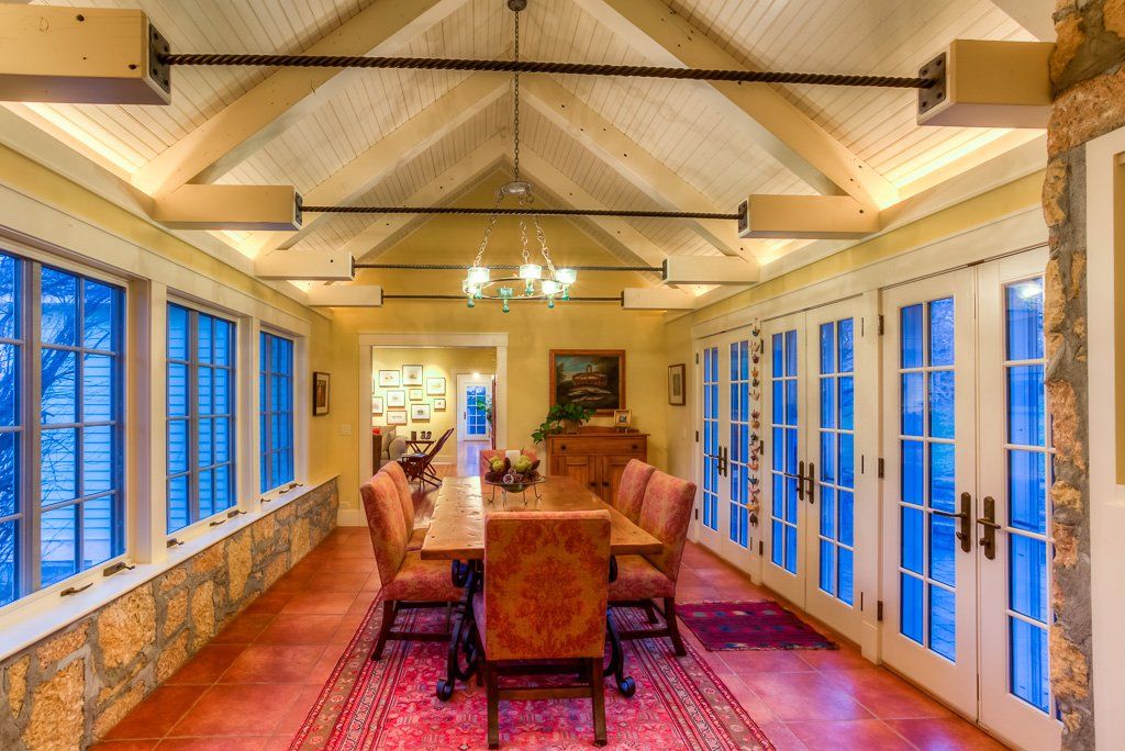 A long dining room with a table and chairs and lots of windows.