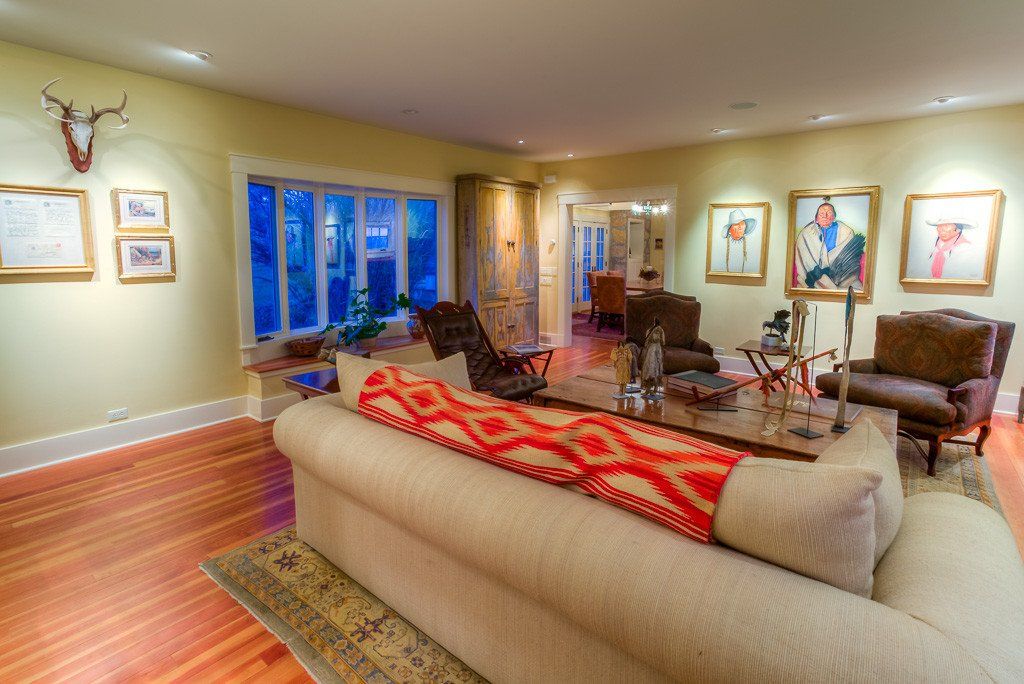 A living room with a couch , chairs , and paintings on the walls.