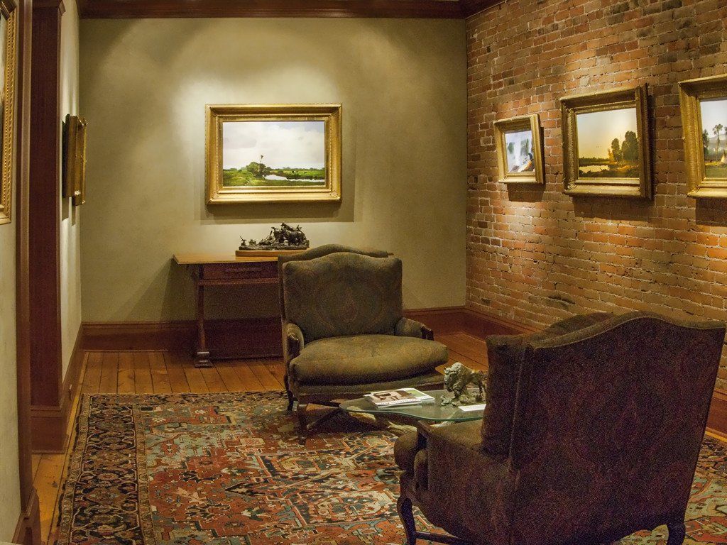 A living room with chairs and paintings on the wall
