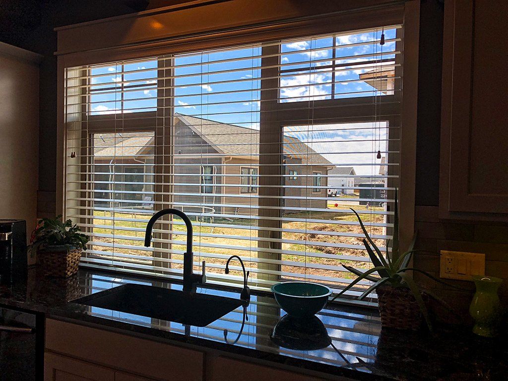 A kitchen with a sink and a window with blinds.
