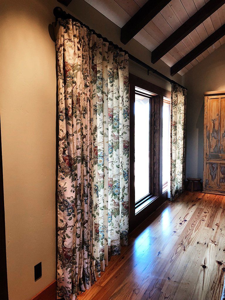A bedroom with hardwood floors and floral curtains