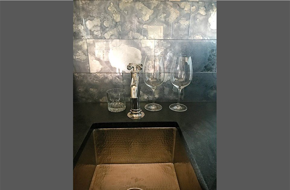 Two wine glasses are sitting on a counter next to a sink.