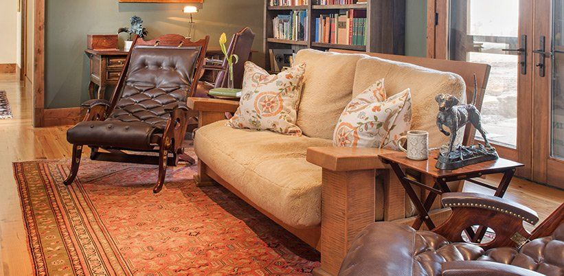 A living room with a couch , chair , table and rug.