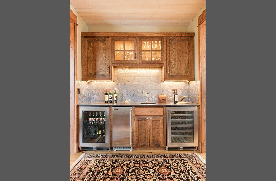 A kitchen with stainless steel appliances and wooden cabinets and a rug on the floor.
