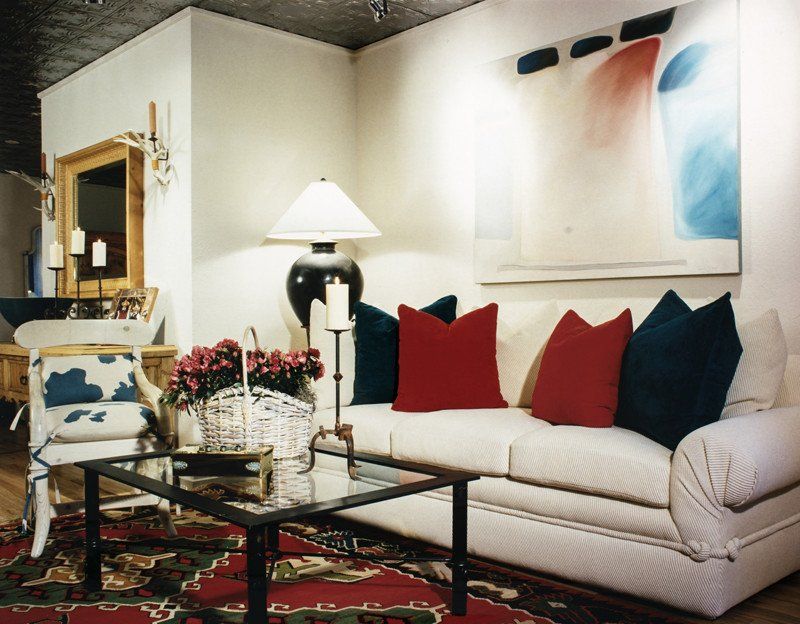 A living room with a white couch and red and blue pillows