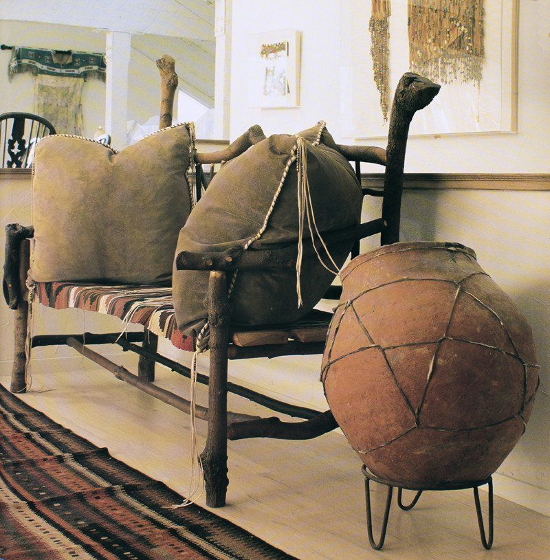 A wooden bench with pillows and a large brown vase