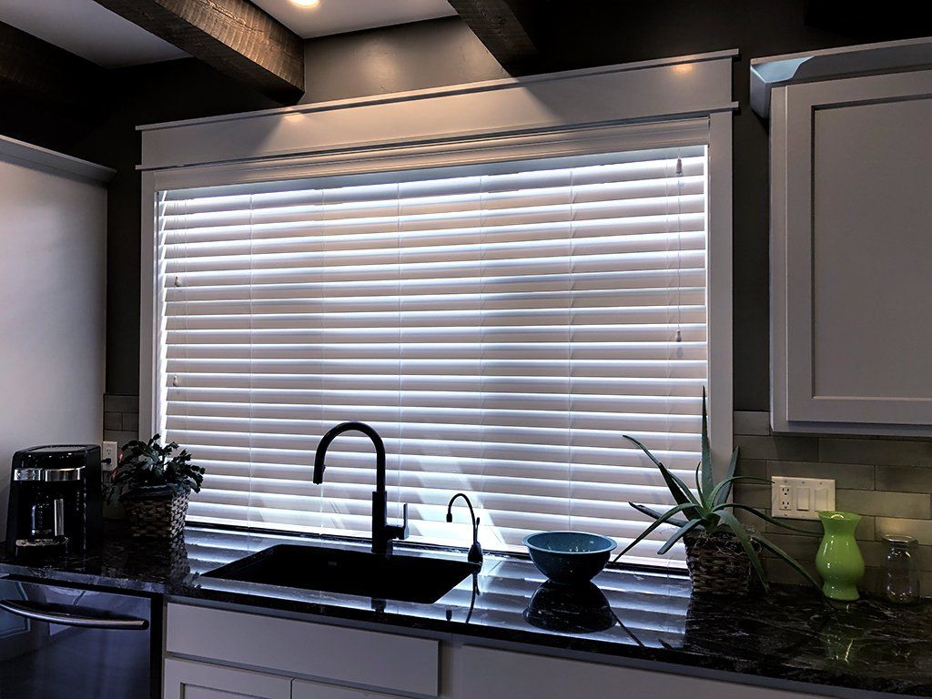 A kitchen with a sink and a window with blinds