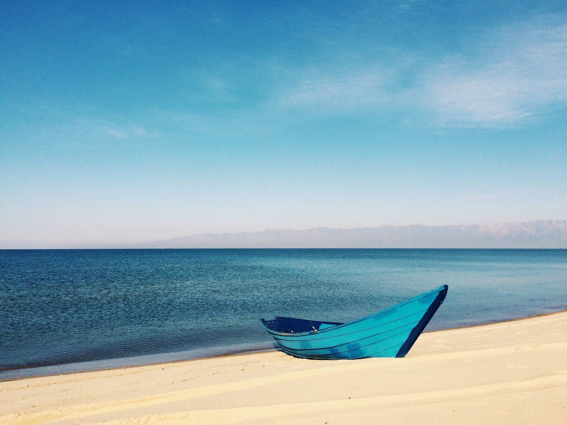 Blaue Hängematte an einem Sandstrand neben einem ruhigen Ozean unter klarem Himmel