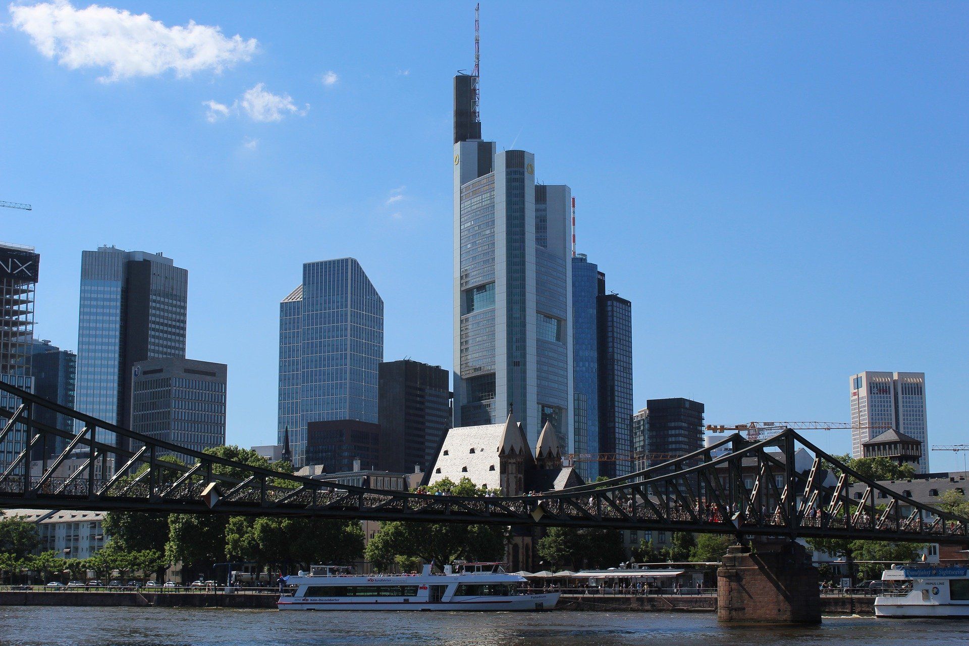 Stadtsilhouette mit modernen Wolkenkratzern hinter einer Brücke über einen Fluss unter klarem, blauem Himmel