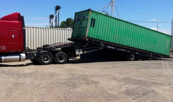 The Tilt bed truck delivering a 40' shipping container