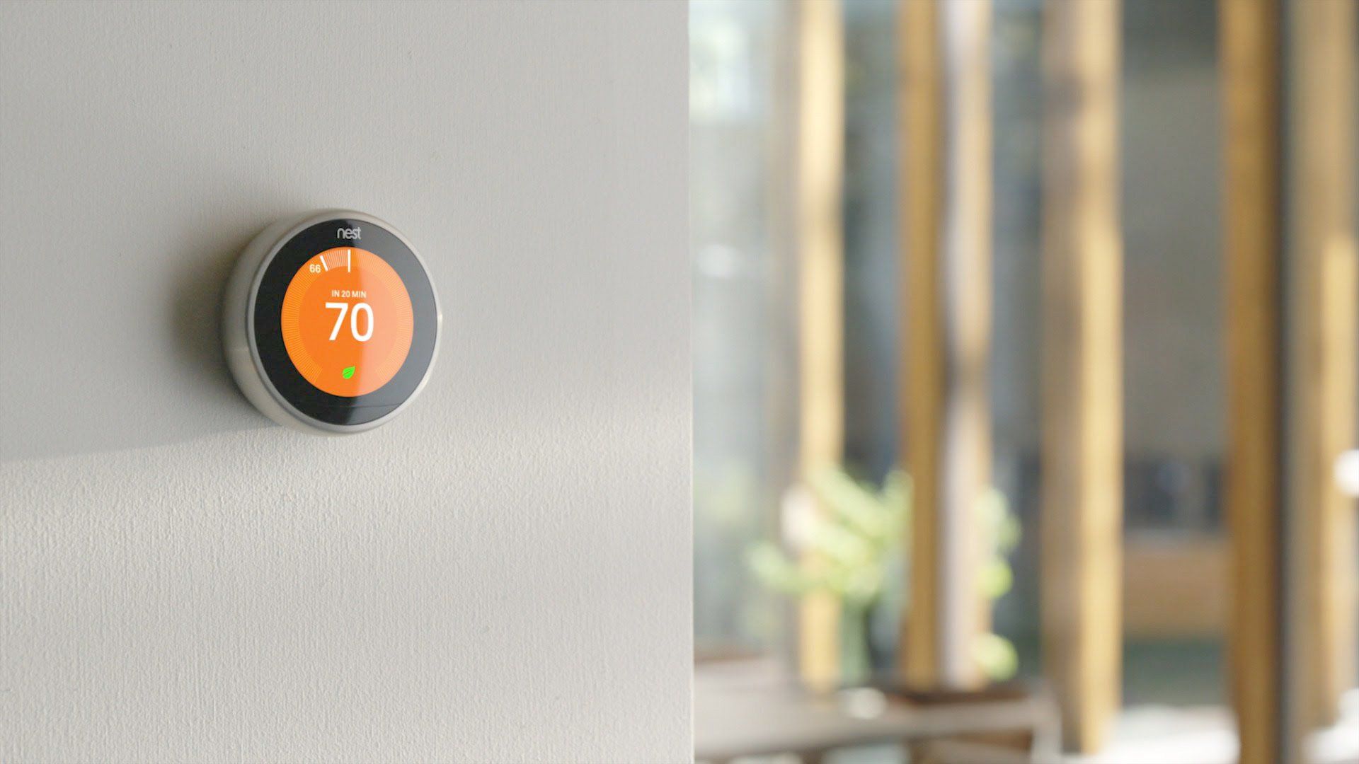 A smart thermostat is hanging on a wall in a living room.