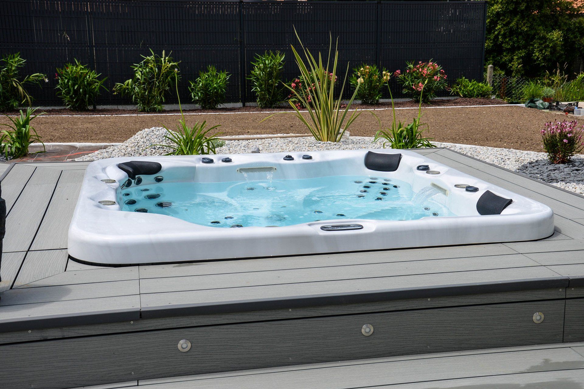 Un jacuzzi blanc est posé sur une terrasse en béton
