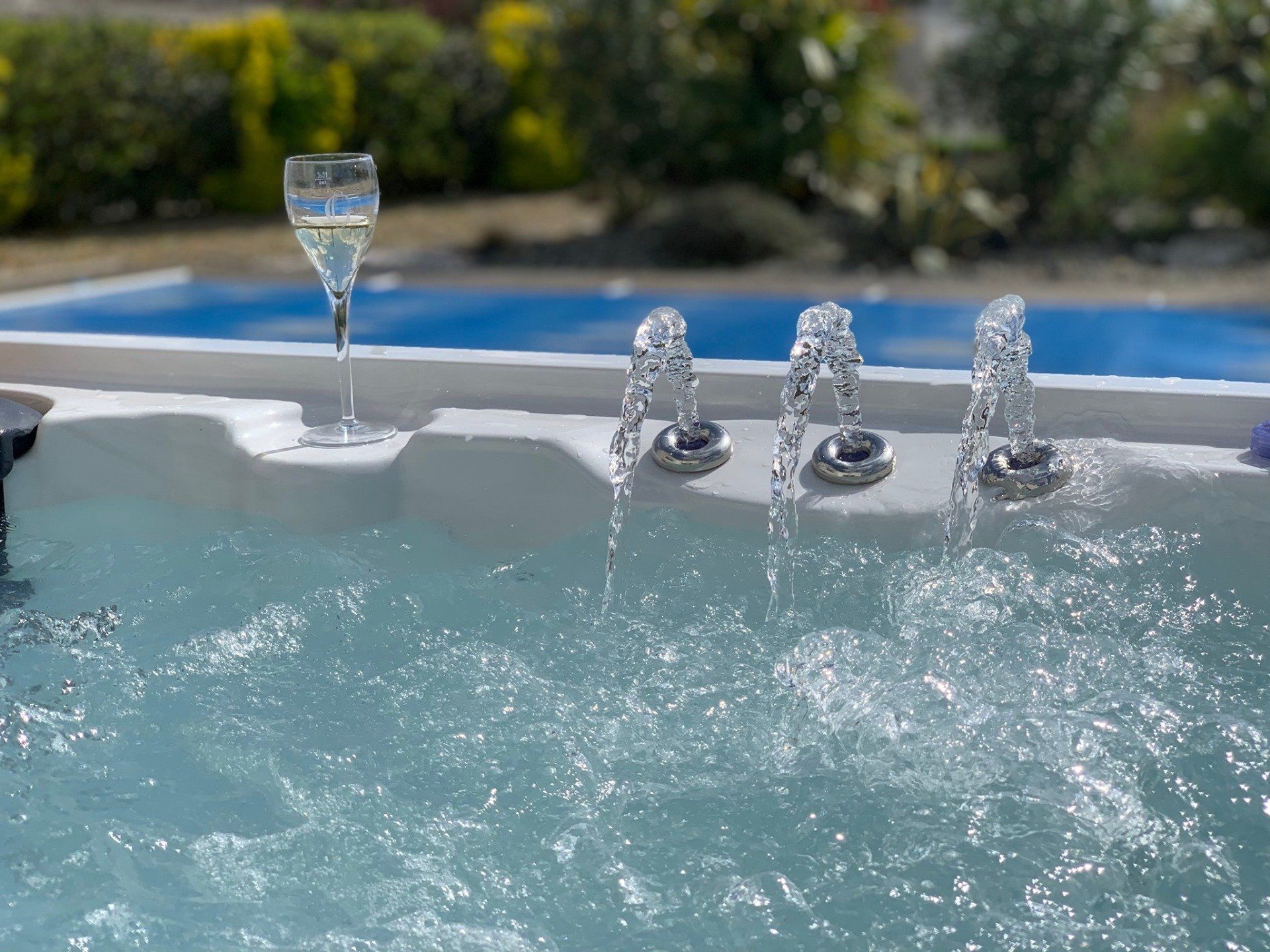 Un verre de vin est posé dans un jacuzzi à côté d'une piscine.