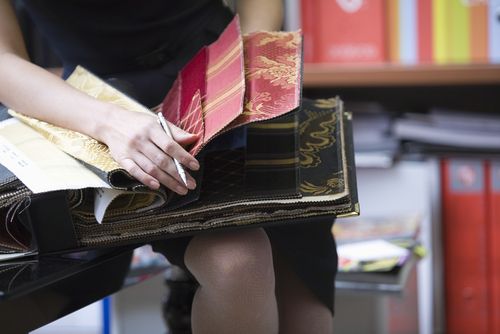 Woman going through a sample book with various types of fabric for upholstery in Sowerby Bridge