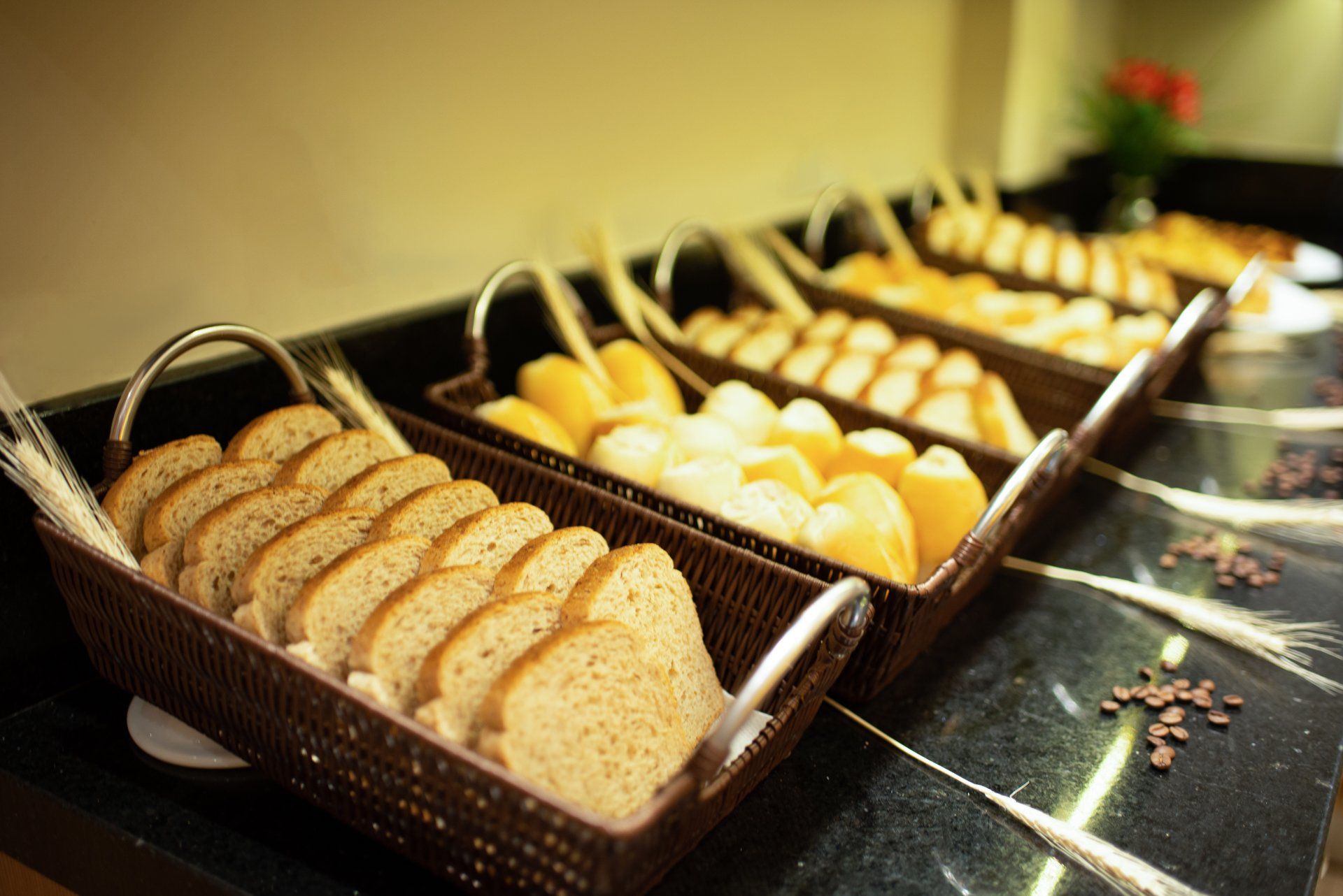 Cestas de pão, com vários tipos de pão fatiado, sobre um balcão preto.