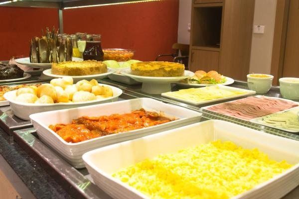 Mesa de bufê com comidas variadas, incluindo bolos, saladas e pratos quentes.