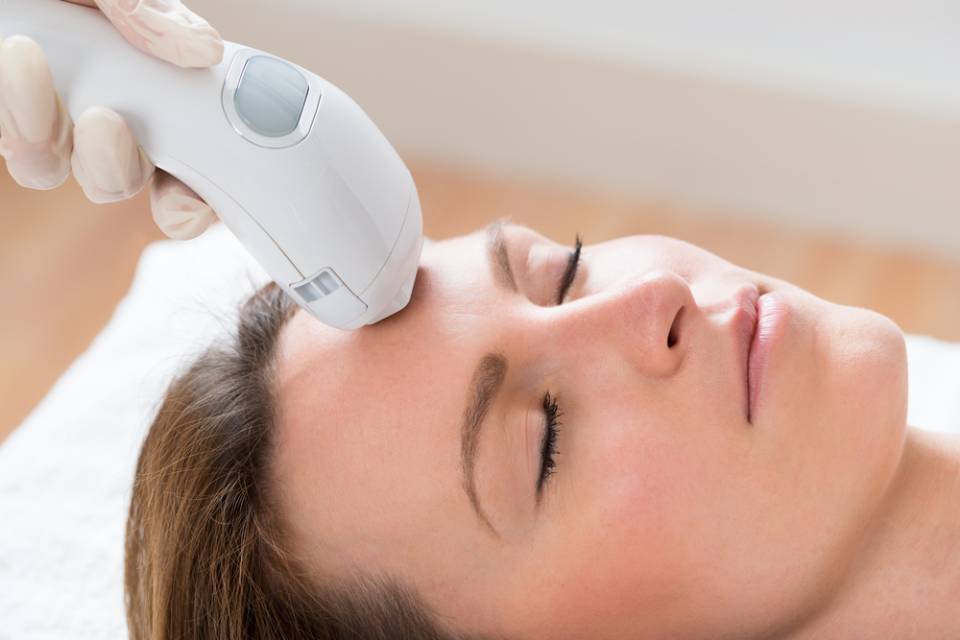 Donna che riceve un trattamento viso con un dispositivo sulla fronte.