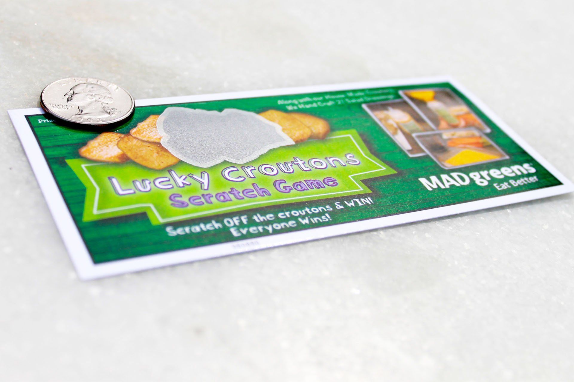 A lucky creations scratch game is sitting on a table next to a quarter.