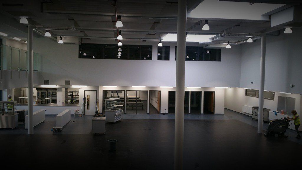 Empty modern retail or showroom interior with white walls, dark floor, shelves, and ceiling lights