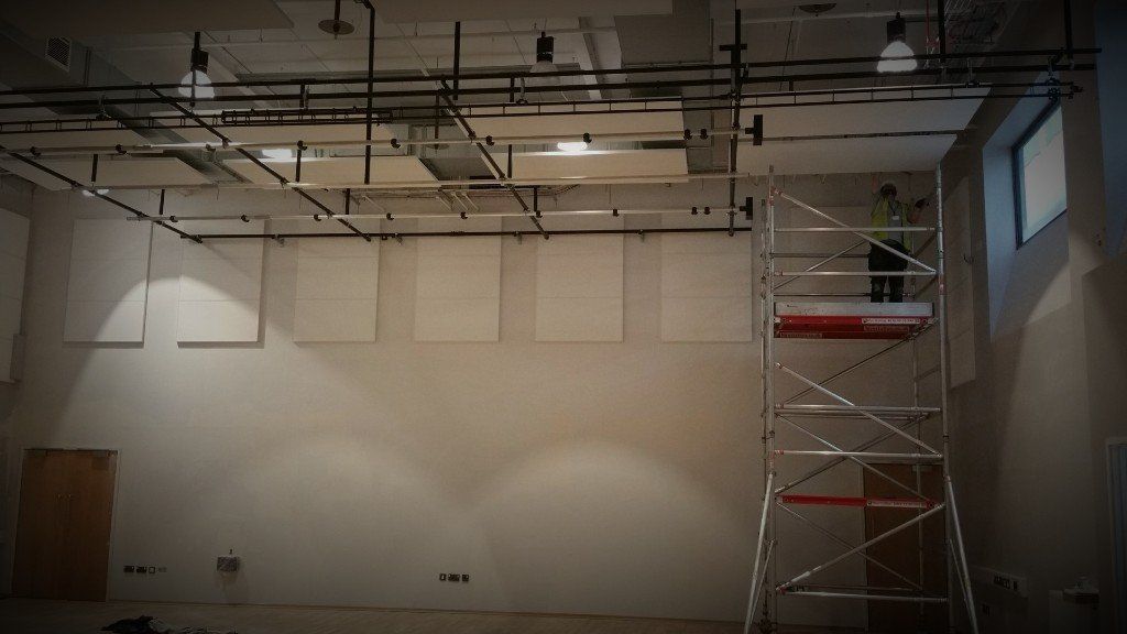 Empty indoor room with scaffolding on the right and ceiling lights overhead