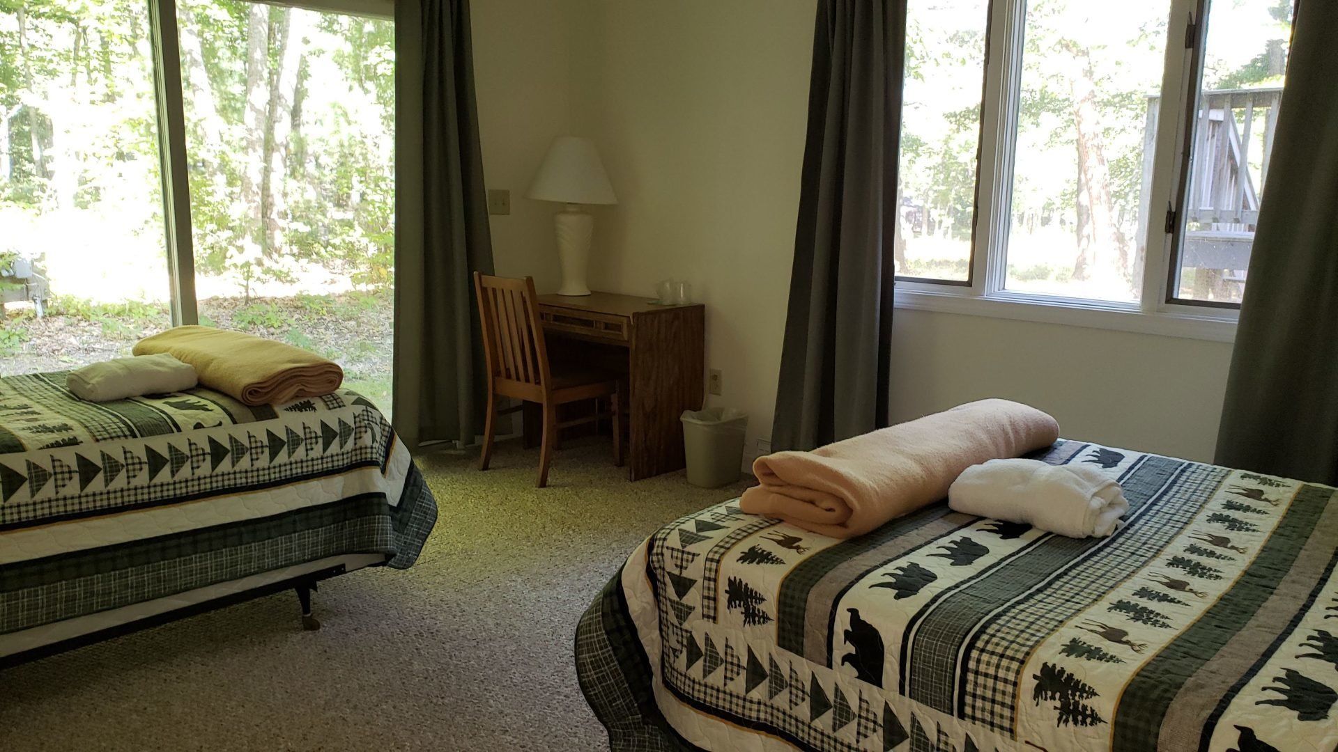 A bedroom with two beds , a desk , and a large window.