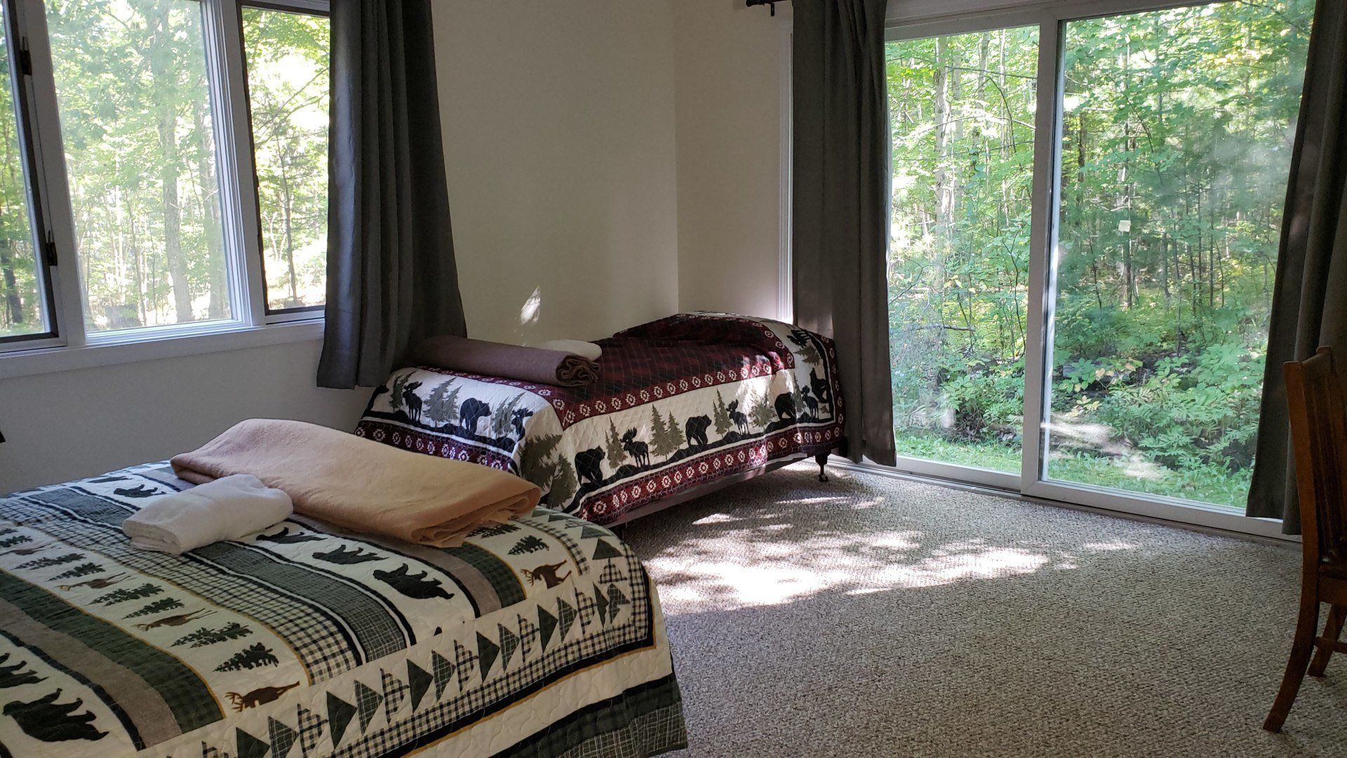 A bedroom with two beds and a sliding glass door.