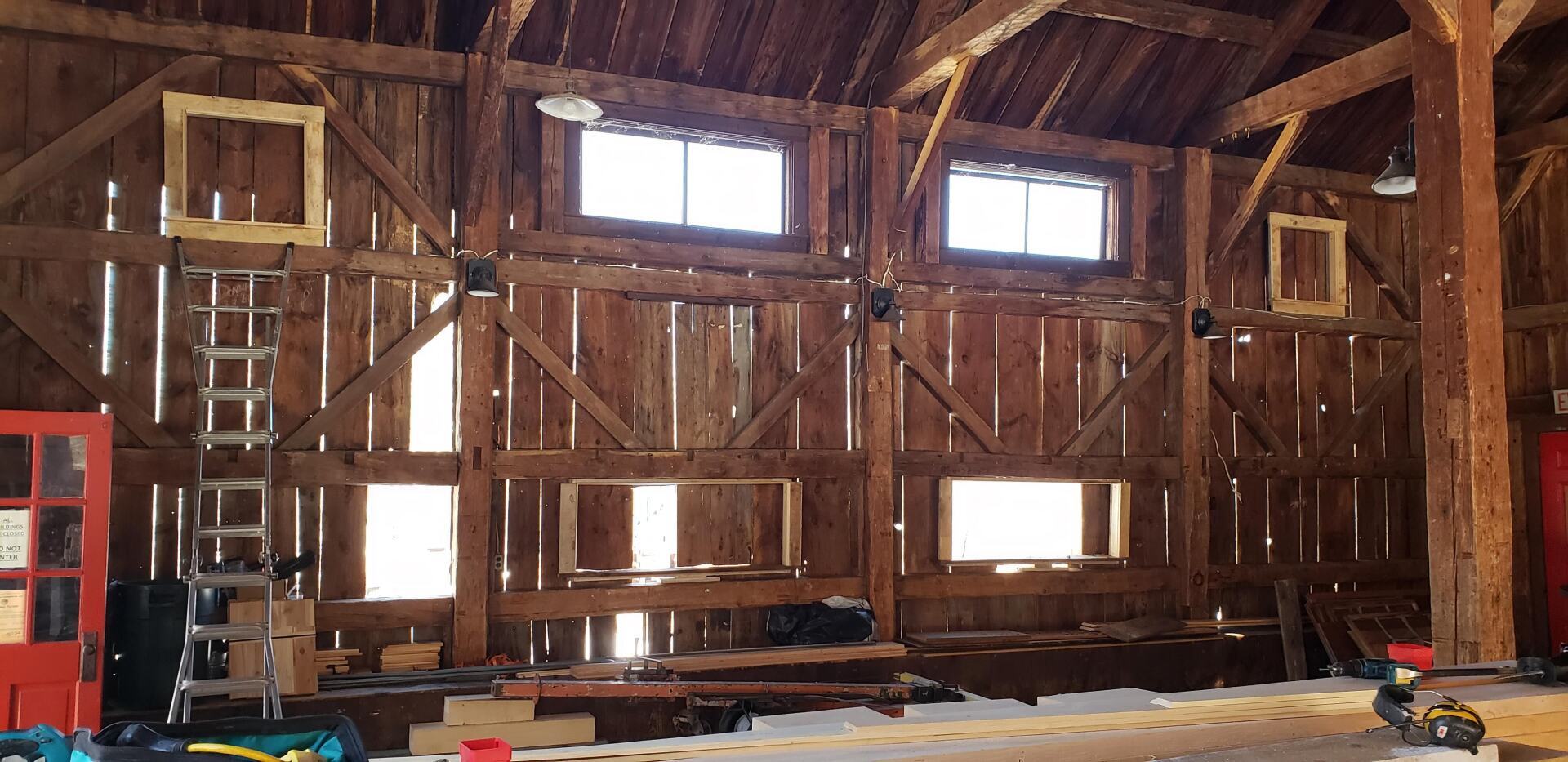 A large wooden barn with a lot of windows and a red door.