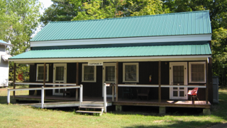 A small house with a green roof and a porch