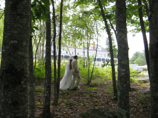 A bride and groom are walking through the woods