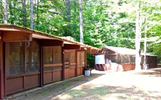 A house with a screened in porch in the middle of a forest.