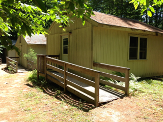 A yellow house with a wooden ramp leading to it