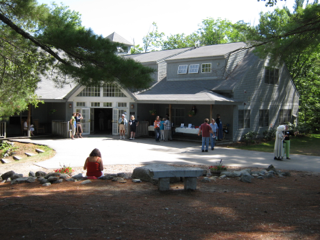 A group of people are gathered in front of a large house