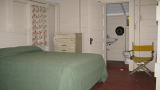 A bedroom with a bed a dresser and a chair
