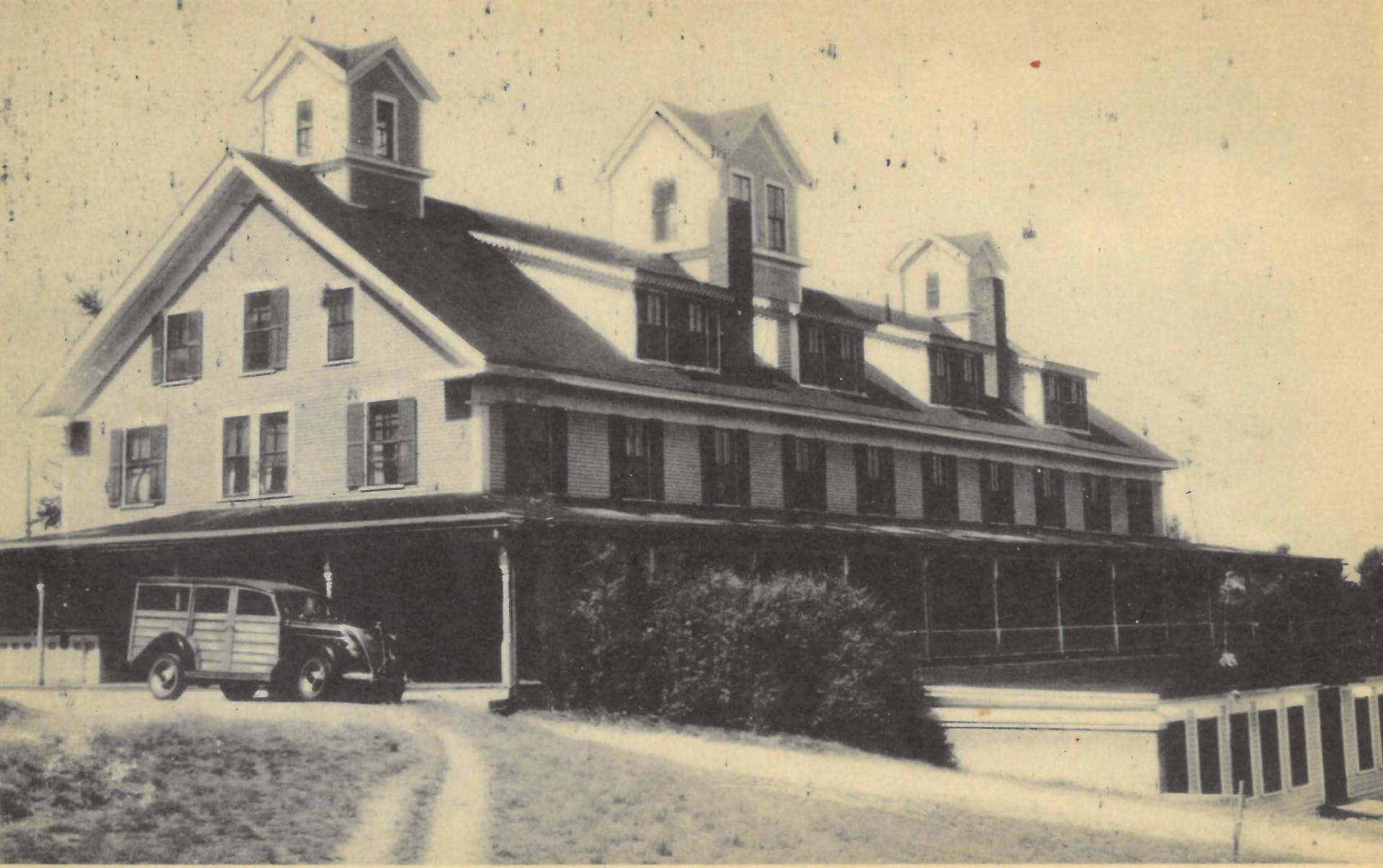 A black and white photo of a large building with a car parked in front of it
