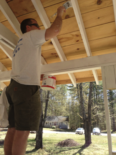 A man is painting a wooden roof with a brush