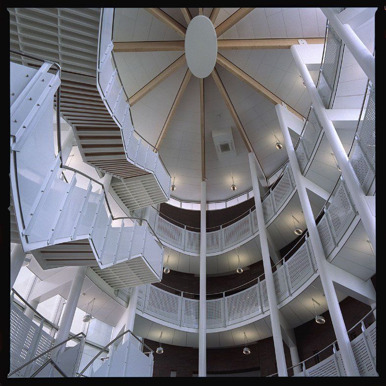 Runder Atrium mit weißen Treppen und Geländern, Blick nach oben zu einem kuppelförmigen Oberlicht