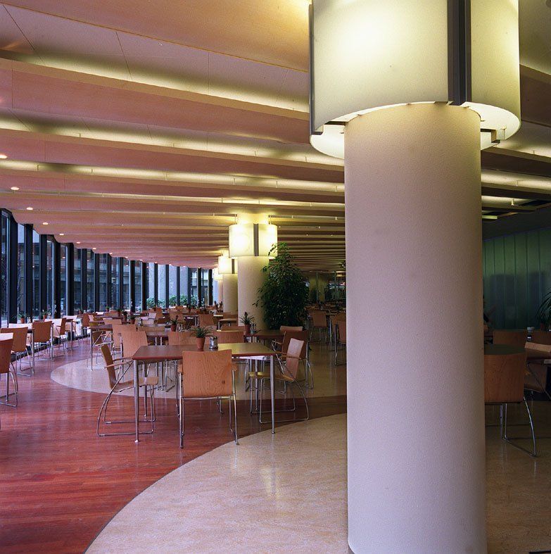 Modernes Restaurantinterieur mit geschwungenen Sitzgelegenheiten, warmer Beleuchtung und einer großen weißen Säule