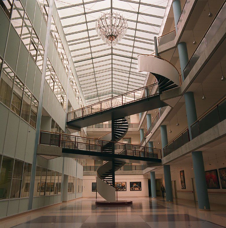 Modernes Atrium mit Wendeltreppe, Glaswänden und Oberlichtdecke