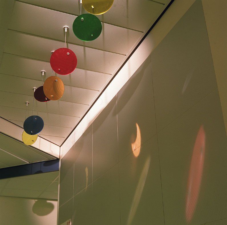Bunte Hängekugeln in einem modernen Flur mit schrägen Deckenpaneelen und grünen Wänden