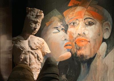 Abstrakte Kunstausstellung mit einer skulptierten Büste und bemalten Gesichtern in Erdtönen
