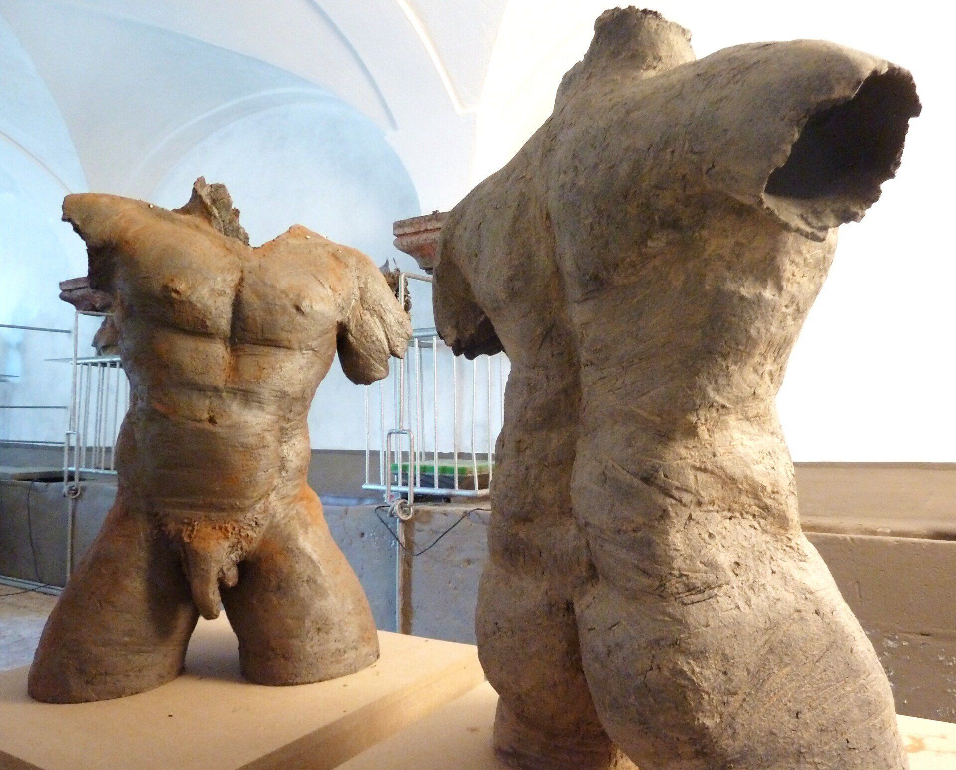 Zwei große, kopflose Torsoskulpturen in einer hellen Museumsgalerie, eine nach vorn und die andere abgewandt.