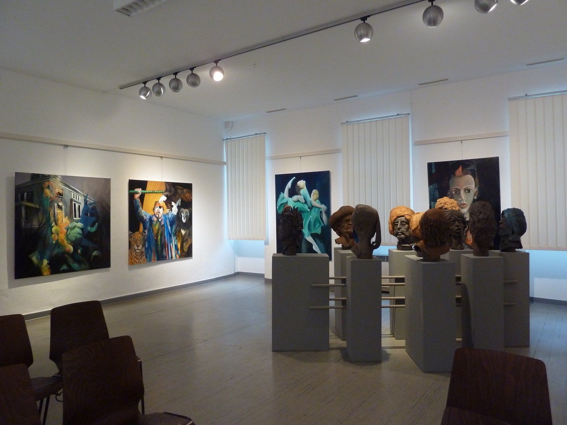 Kunstgalerie mit abstrakten Gemälden und Skulpturen in einem hellen, weißen Ausstellungsraum.