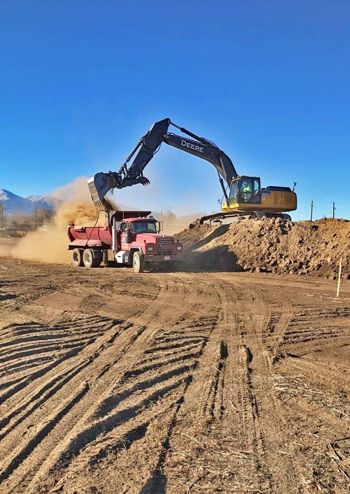 Excavator dumps dirt into truck