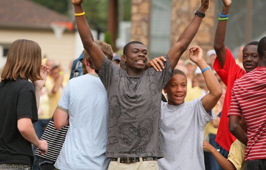 Group of people celebrating outdoors with arms raised in excitement.