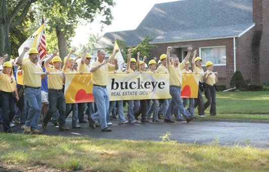 Group in yellow shirts and hard hats marching with a banner that reads 
