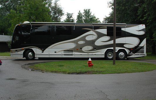 Black and white recreational vehicle with flame-like designs parked on a grassy patch.